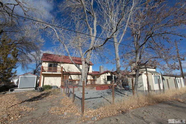 view of front of house with a deck and a storage shed