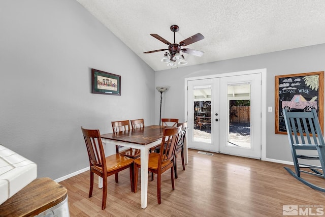 dining room with french doors, a textured ceiling, ceiling fan, light hardwood / wood-style flooring, and lofted ceiling