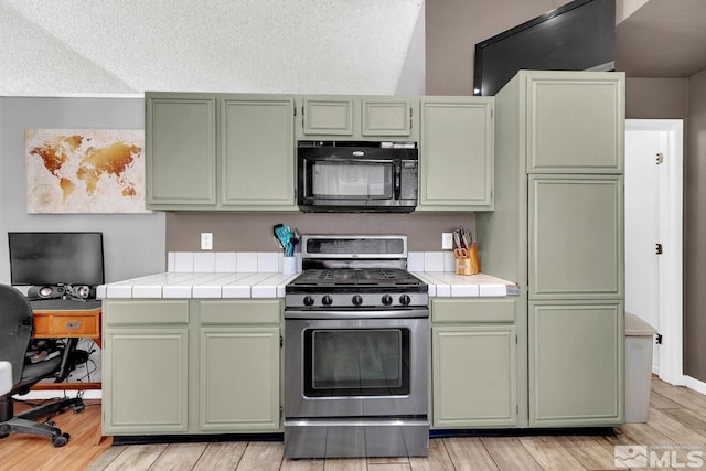 kitchen featuring tile countertops, green cabinets, stainless steel range with gas cooktop, and a textured ceiling