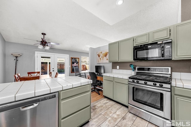 kitchen with tile countertops, french doors, stainless steel appliances, and green cabinetry