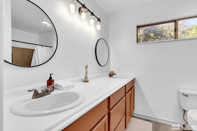 bathroom featuring wood-type flooring, vanity, toilet, and curtained shower