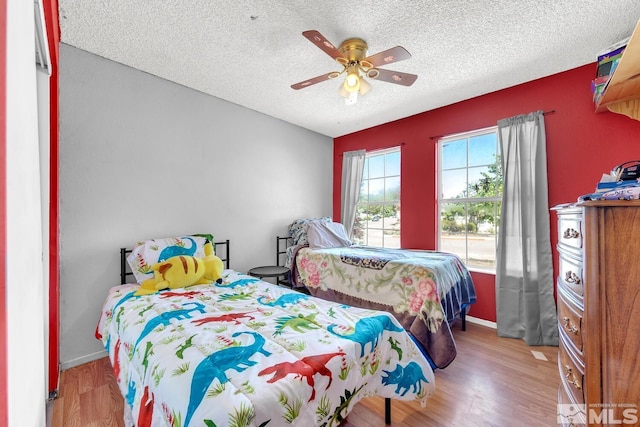 bedroom featuring ceiling fan, light hardwood / wood-style floors, and a textured ceiling