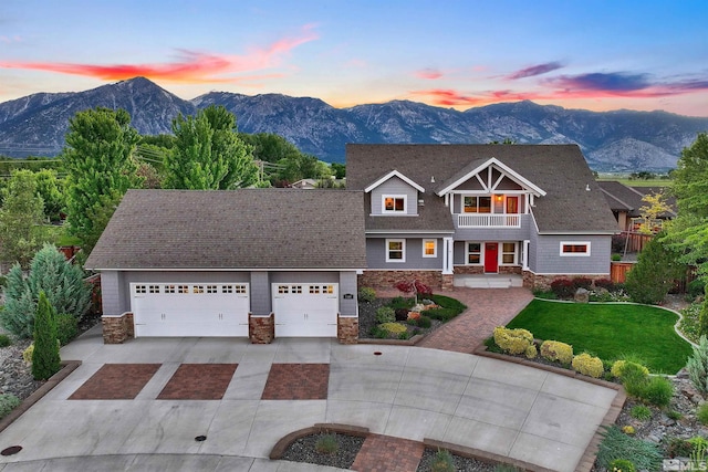 view of front of house featuring a lawn, a mountain view, a garage, and a balcony