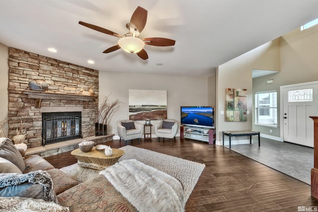 living room with hardwood / wood-style flooring, ceiling fan, and a stone fireplace