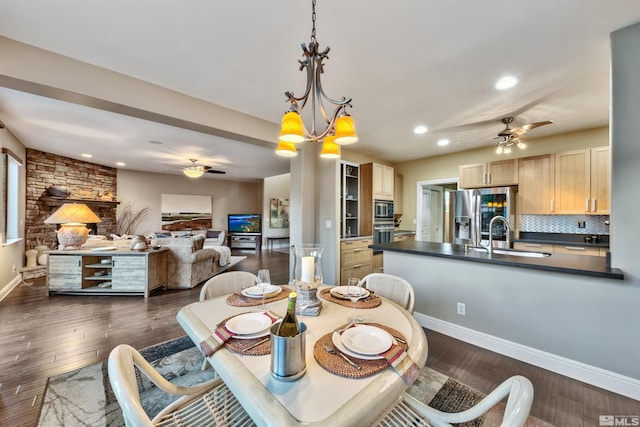 dining space with ceiling fan with notable chandelier, dark hardwood / wood-style flooring, and sink