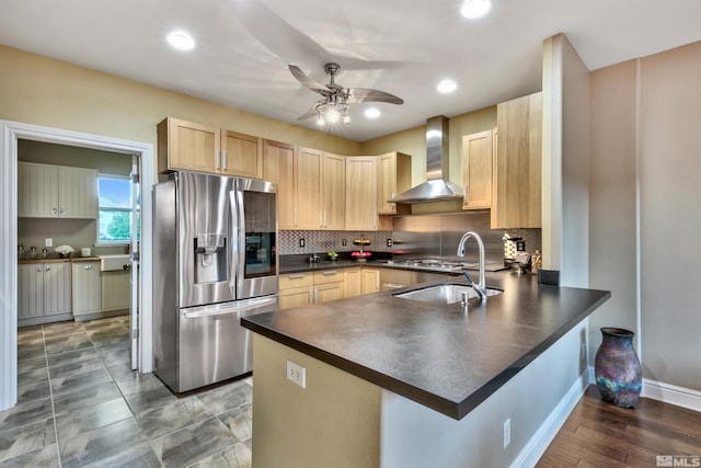 kitchen with light brown cabinets, wall chimney range hood, ceiling fan, kitchen peninsula, and stainless steel appliances