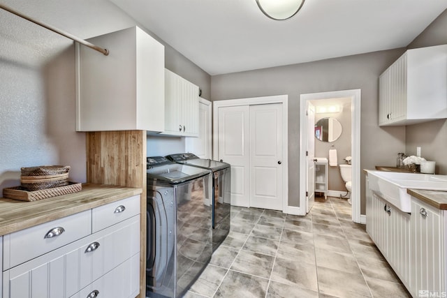 kitchen with white cabinetry, sink, light tile patterned floors, and independent washer and dryer