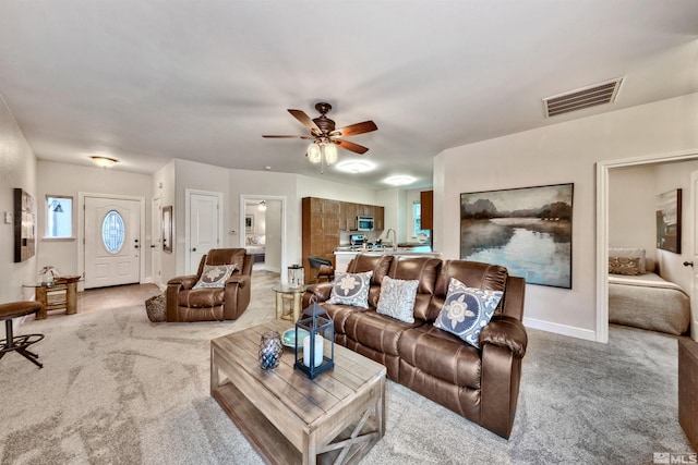 living room featuring light colored carpet, ceiling fan, and sink