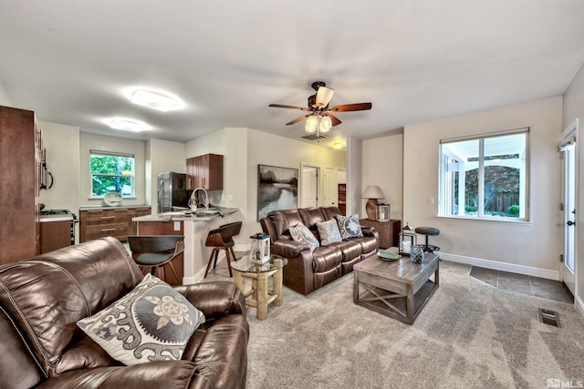 living room featuring light carpet, ceiling fan, and sink