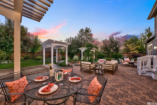 patio terrace at dusk featuring a pergola and an outdoor living space