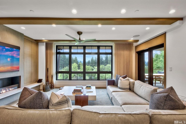 living room featuring ceiling fan, a wealth of natural light, a large fireplace, and wooden walls