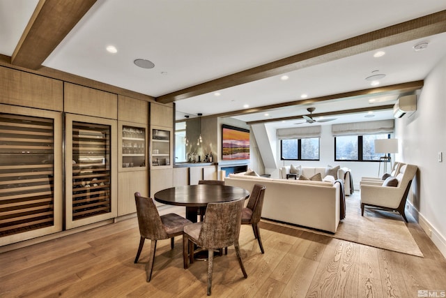 dining room featuring ceiling fan, a wall mounted AC, beam ceiling, and light hardwood / wood-style flooring