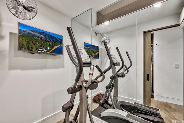 workout room with an AC wall unit and hardwood / wood-style floors