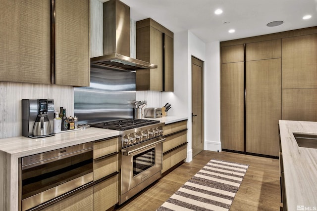 kitchen featuring appliances with stainless steel finishes, wall chimney range hood, backsplash, and light hardwood / wood-style flooring