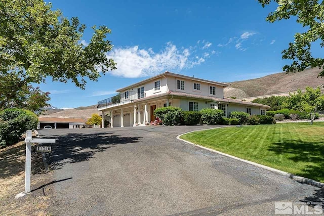 view of front of home featuring a mountain view, a balcony, a front yard, and a garage