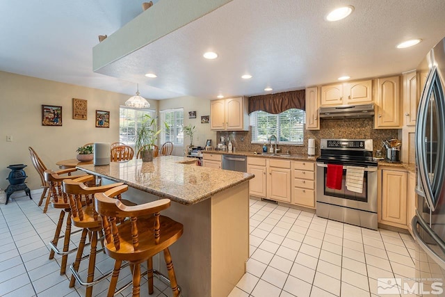 kitchen with a kitchen bar, decorative backsplash, sink, and appliances with stainless steel finishes