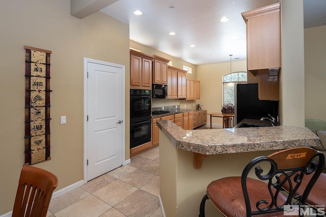 kitchen featuring kitchen peninsula, sink, a breakfast bar area, and black appliances