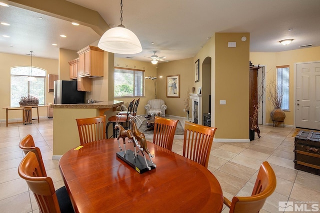 dining space with a wealth of natural light, ceiling fan, and light tile patterned flooring