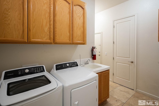 laundry room featuring washing machine and dryer, sink, light tile patterned floors, and cabinets