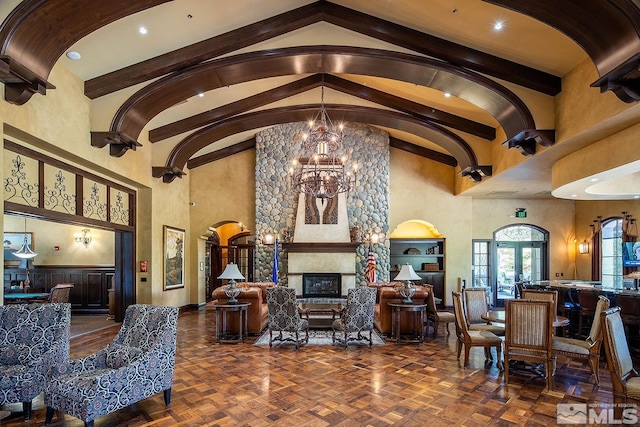 living room featuring dark parquet floors, an inviting chandelier, high vaulted ceiling, and a large fireplace