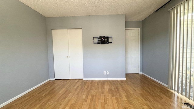 unfurnished bedroom with a closet, a textured ceiling, and light wood-type flooring