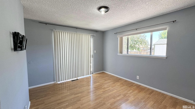 spare room featuring hardwood / wood-style floors and a textured ceiling