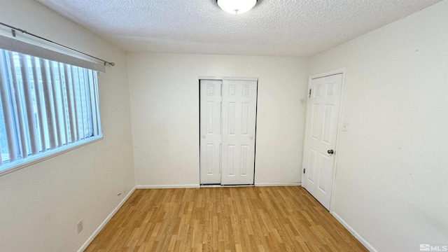 unfurnished bedroom featuring light wood-type flooring, a textured ceiling, and a closet