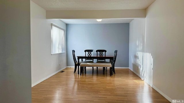 dining area with a textured ceiling and light wood-type flooring