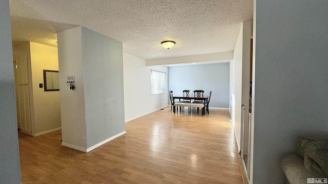 hallway with a textured ceiling and light wood-type flooring