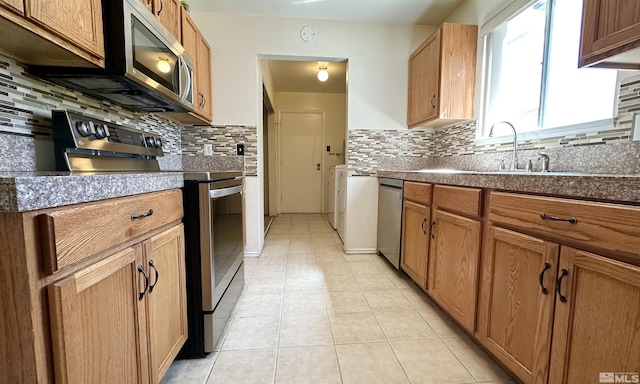 kitchen featuring backsplash, sink, light tile patterned floors, and appliances with stainless steel finishes