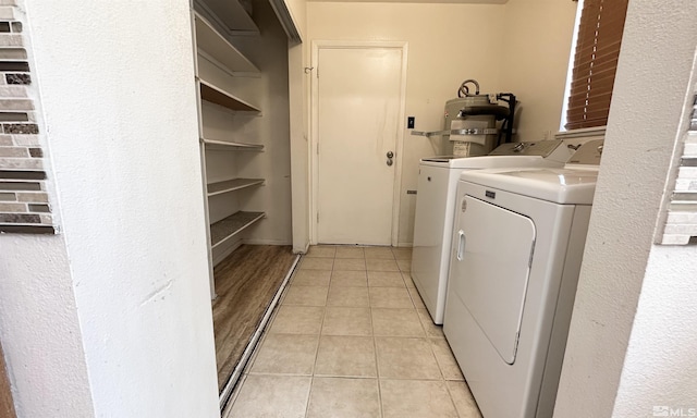 clothes washing area with washing machine and clothes dryer, electric water heater, and light tile patterned floors