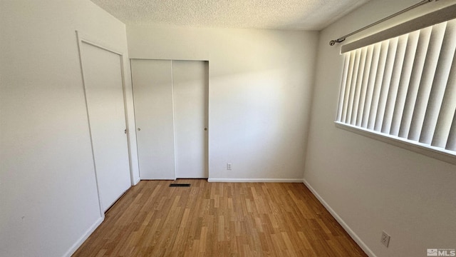 unfurnished bedroom with light hardwood / wood-style floors and a textured ceiling