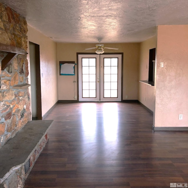 spare room with a textured ceiling, french doors, dark wood finished floors, and baseboards