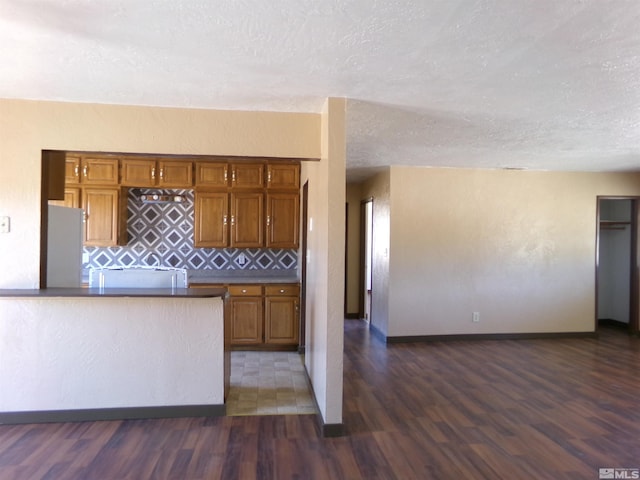 kitchen with dark hardwood / wood-style floors, a textured ceiling, and tasteful backsplash