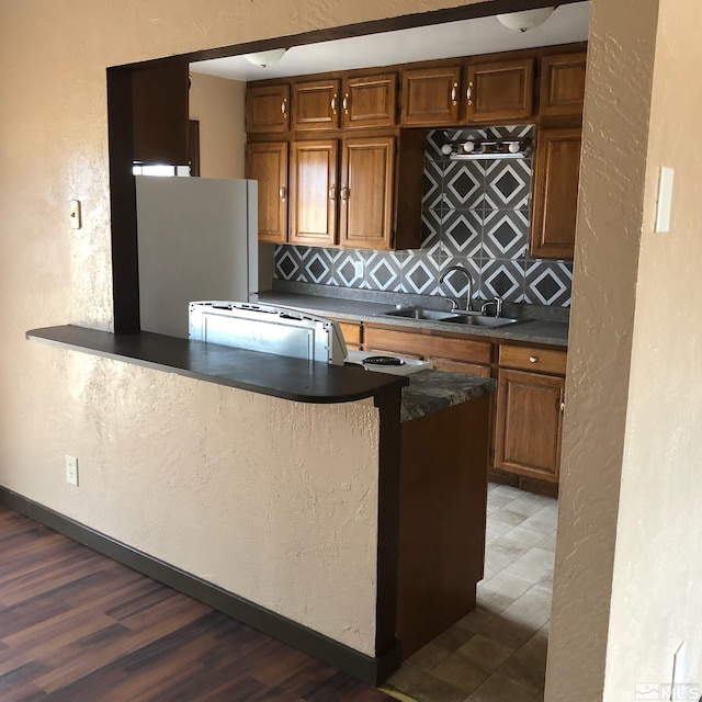 kitchen featuring dark countertops, backsplash, a sink, and freestanding refrigerator