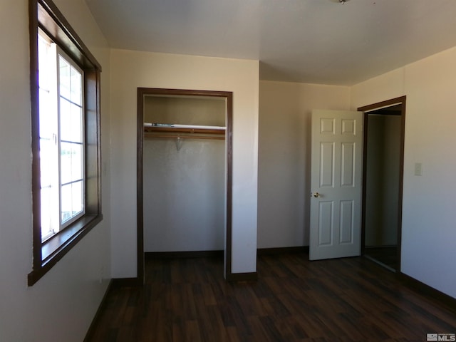 unfurnished bedroom with dark wood-type flooring, a closet, multiple windows, and baseboards