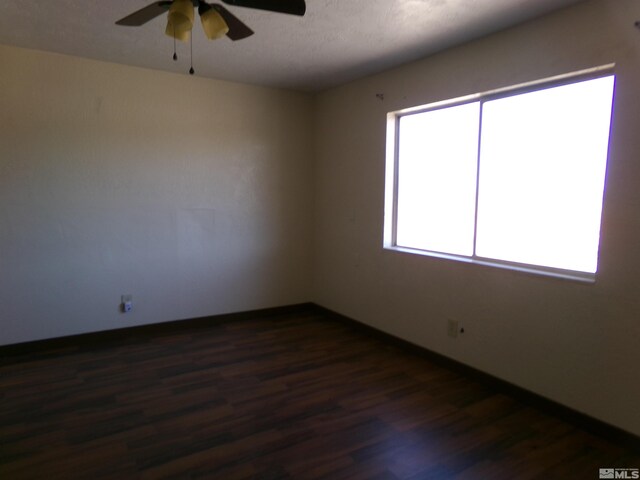 empty room featuring dark wood-type flooring, ceiling fan, and a textured ceiling