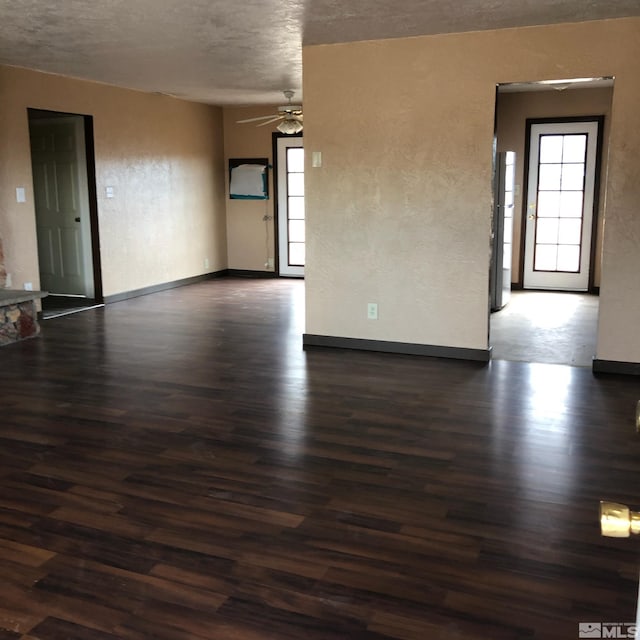 unfurnished room with dark wood-style flooring, a healthy amount of sunlight, and a textured wall