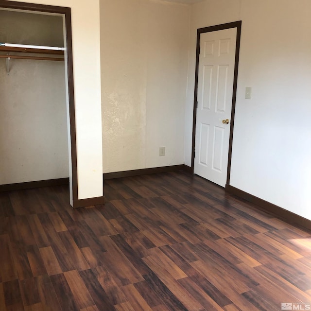 unfurnished bedroom featuring a closet, baseboards, and dark wood-style flooring