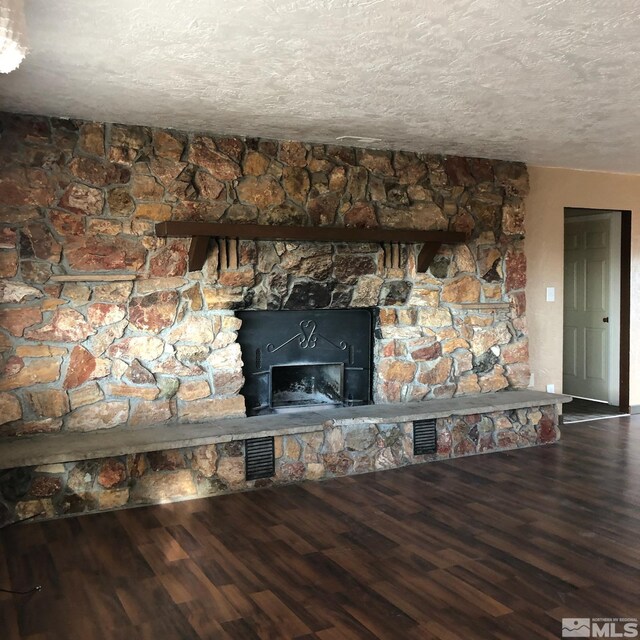 interior details featuring a stone fireplace, a textured ceiling, and hardwood / wood-style floors