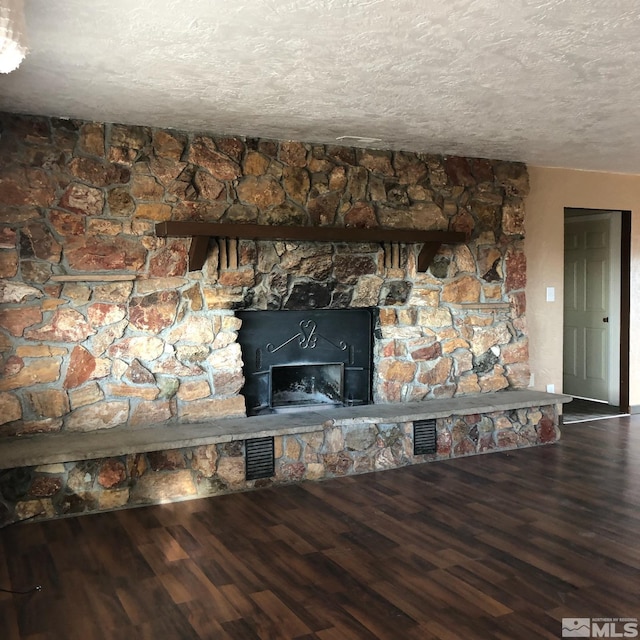 interior details featuring visible vents, a fireplace, a textured ceiling, and wood finished floors