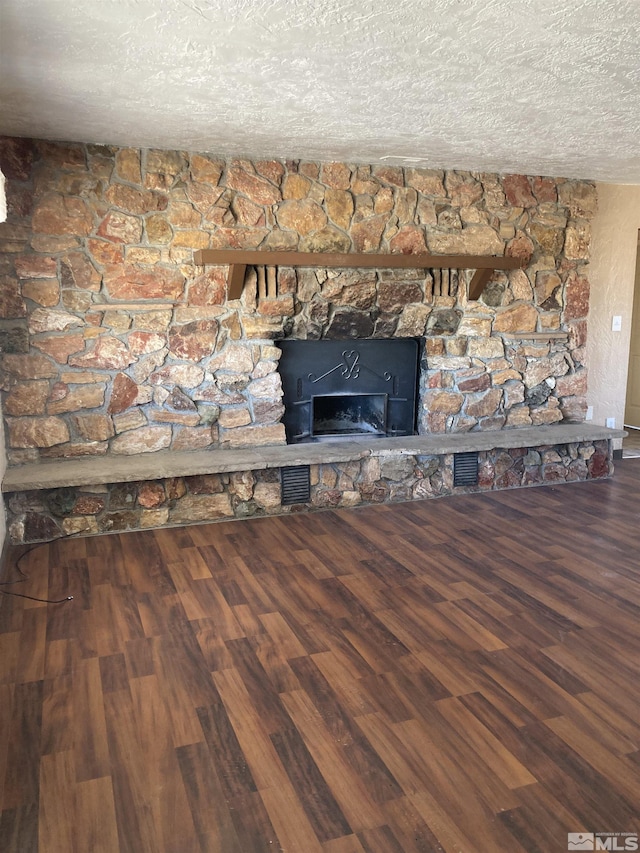 interior details with a textured ceiling, visible vents, a fireplace, and wood finished floors