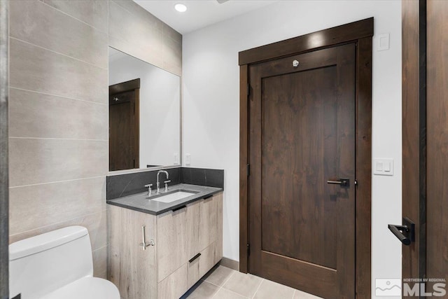 bathroom with tile patterned flooring, vanity, toilet, and tile walls