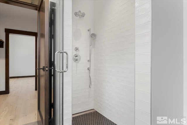 bathroom with hardwood / wood-style flooring and a shower with shower door