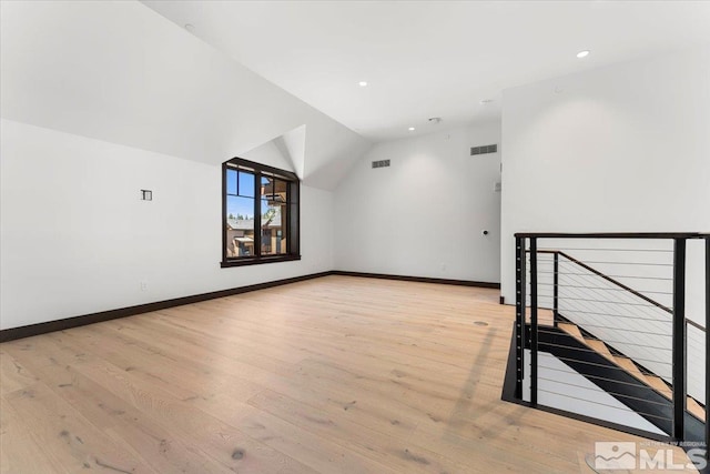 additional living space with vaulted ceiling and light wood-type flooring