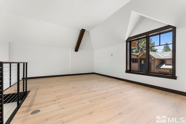 additional living space featuring vaulted ceiling with beams and light wood-type flooring