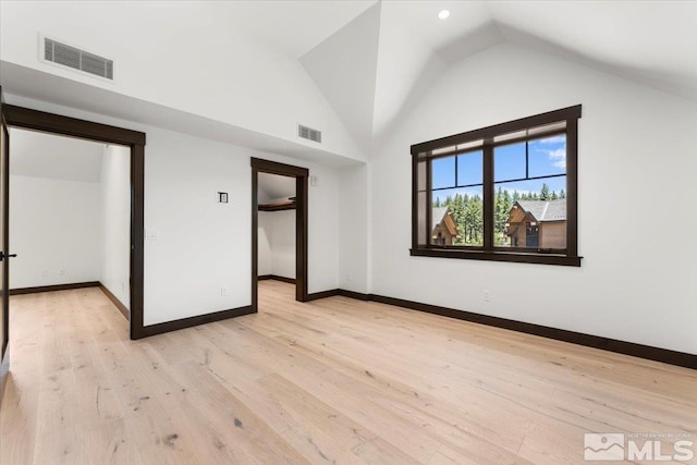 unfurnished bedroom featuring high vaulted ceiling and light wood-type flooring