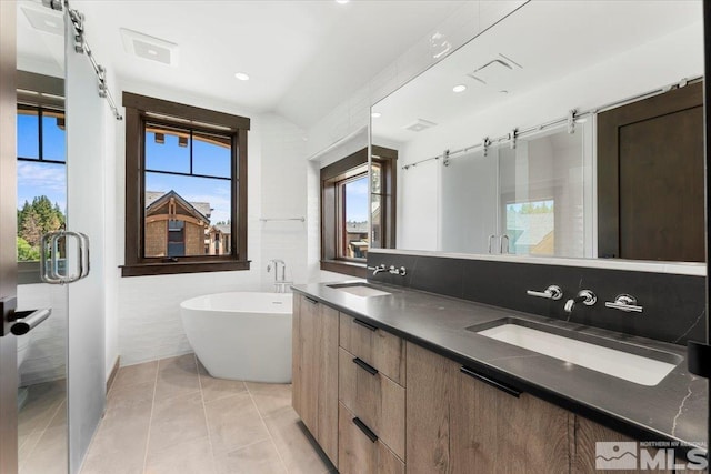 bathroom featuring vanity, lofted ceiling, tile patterned flooring, tile walls, and a tub