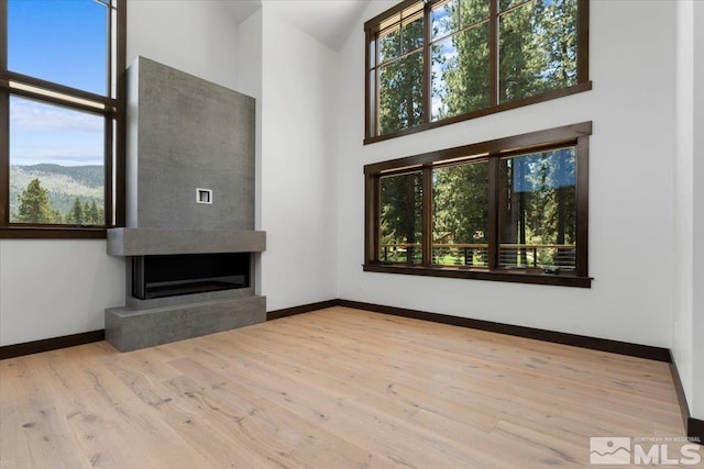 unfurnished living room featuring a mountain view, high vaulted ceiling, and light wood-type flooring