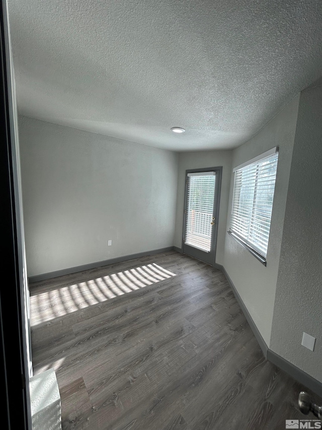 unfurnished room with a textured ceiling and dark hardwood / wood-style flooring